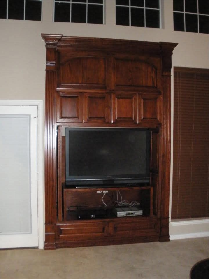 A large flat screen tv is mounted on a wooden entertainment center