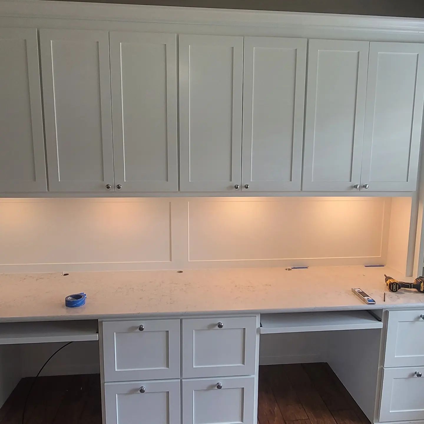A desk with white cabinets and drawers underneath it