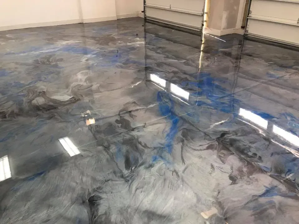 Glossy blue-gray epoxy floor with marbled swirls in an empty room, reflecting overhead lights