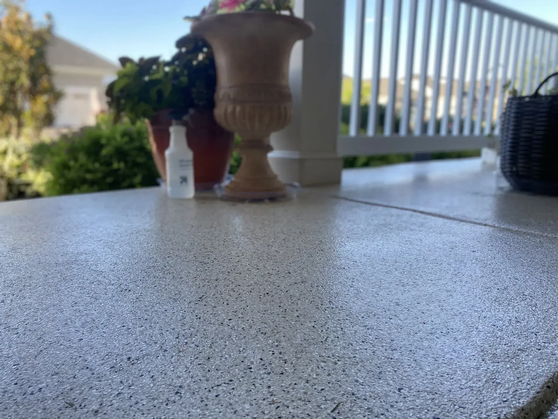 Outdoor patio table with a potted plant, spray bottle, and balcony railing in the background