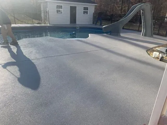 Backyard swimming pool with a cover, a ladder, and a small dog standing at the left edge.