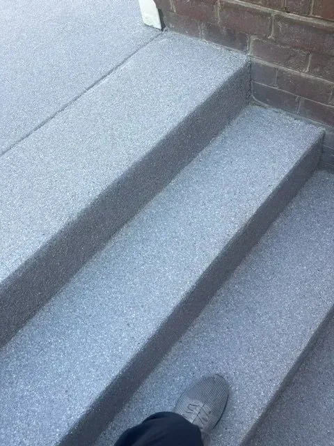 Gray carpeted stairs viewed from above, with a shoe visible at the bottom step