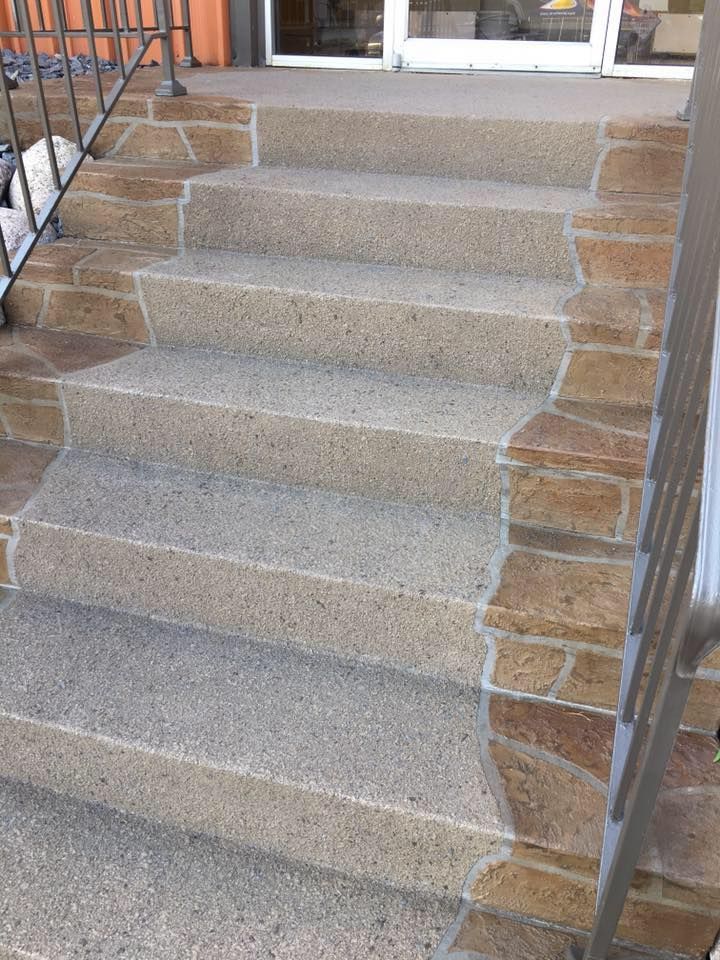 Concrete front steps with metal railings leading up to a porch entrance