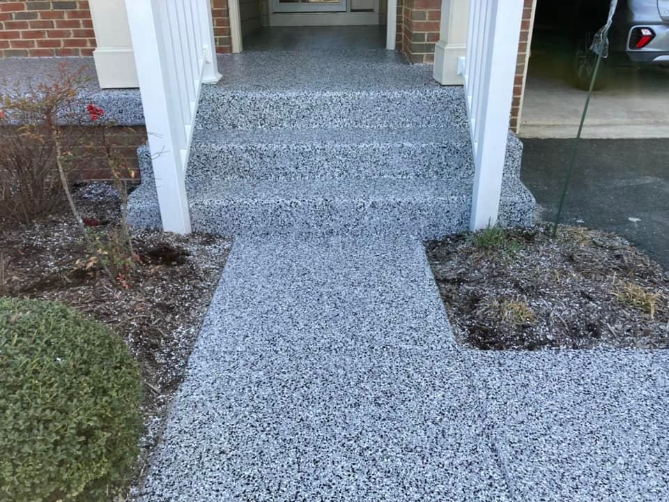 Gravel walkway leading to a front porch with white railings and brick exterior