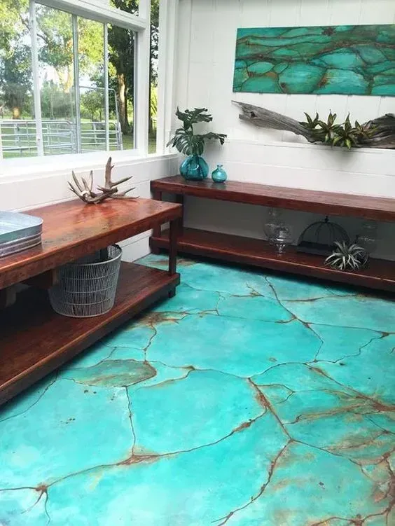 Bright room with turquoise floor, wooden benches, large windows, and teal wall art.