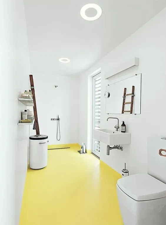 Bright white accessible bathroom with yellow floor, sink, toilet, shower, and wall mirror.
