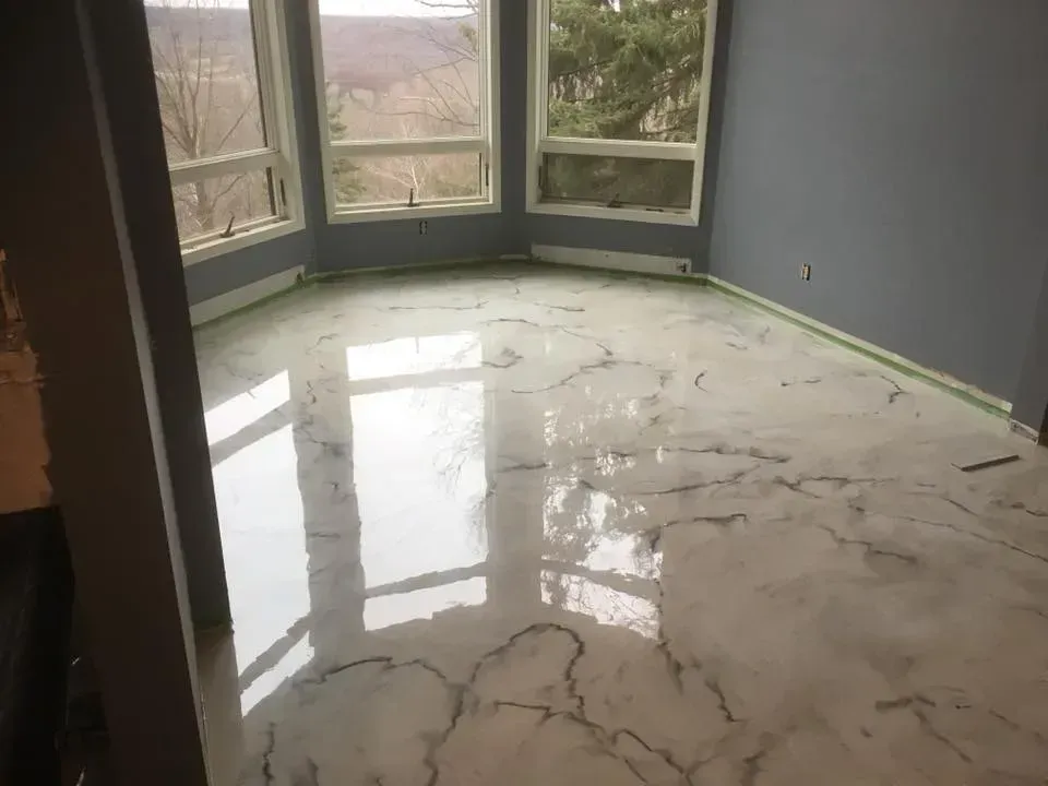 Empty room with glossy marble floor and large bay windows, reflecting daylight.