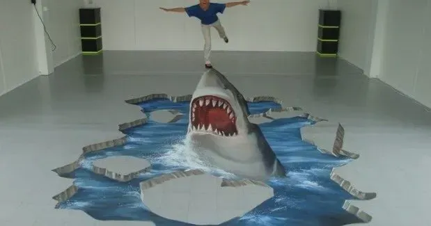 3D shark illusion on a gym floor, with a person posed above it