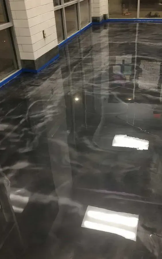 Shiny black floor with water reflections in a hallway, blue tape along the wall edges.