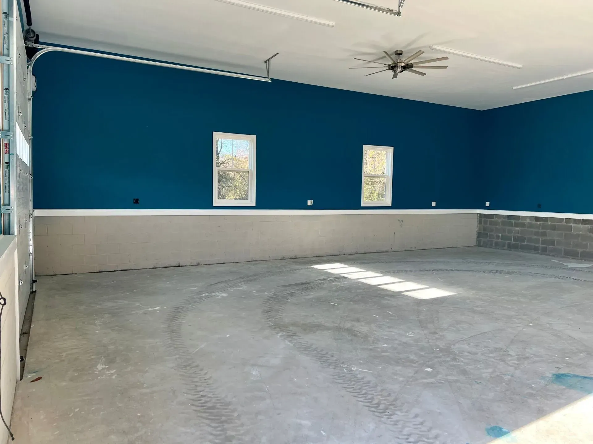 Empty room with blue walls, gray floor, and two narrow windows letting in sunlight