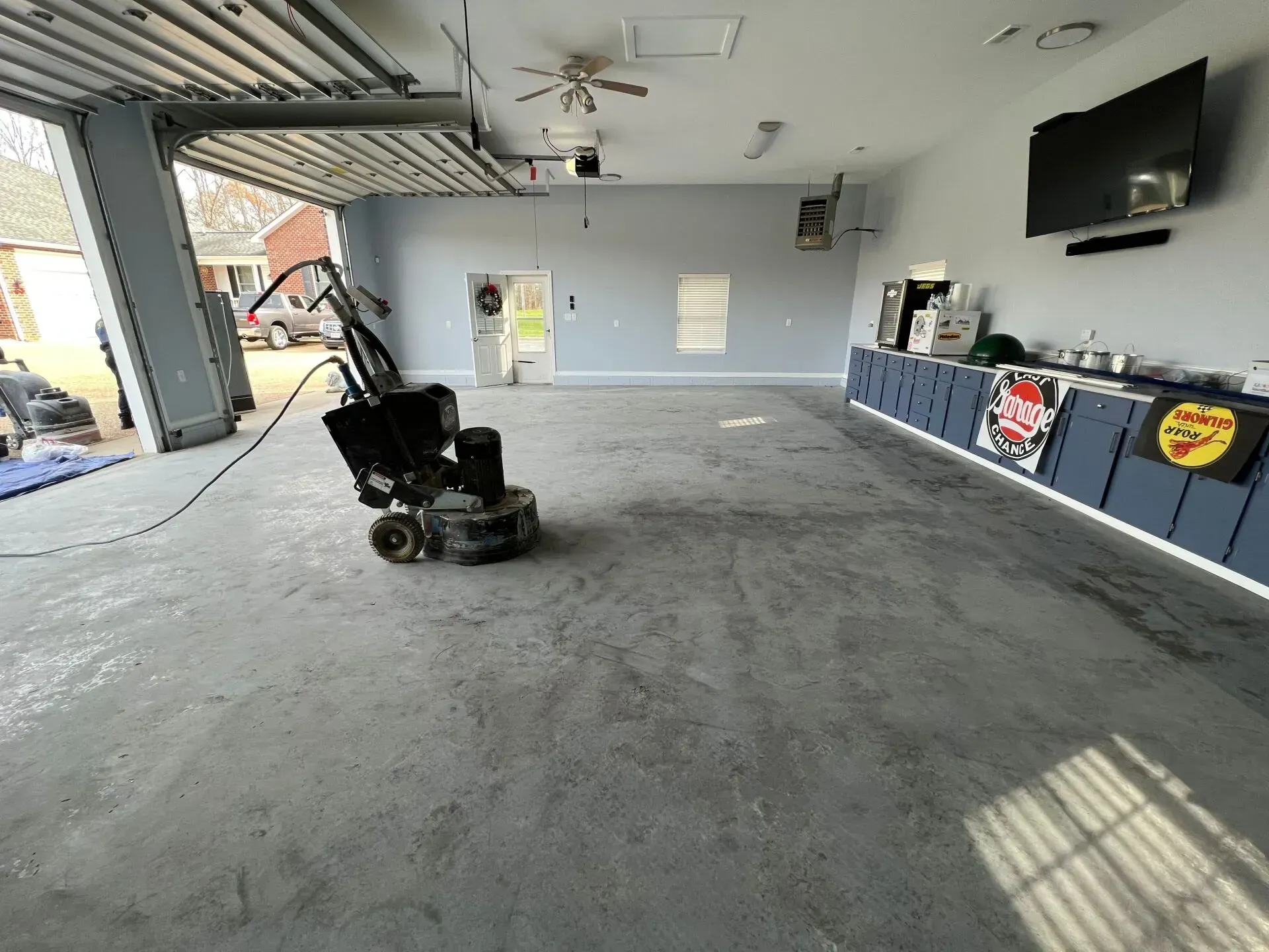 Empty garage interior with a wheelchair near the open bay door and cabinets along the wall