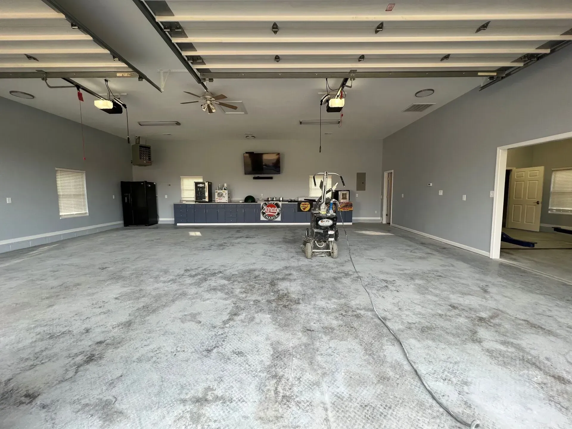 Empty unfinished garage with a concrete floor, gray walls, and a workbench at the back.