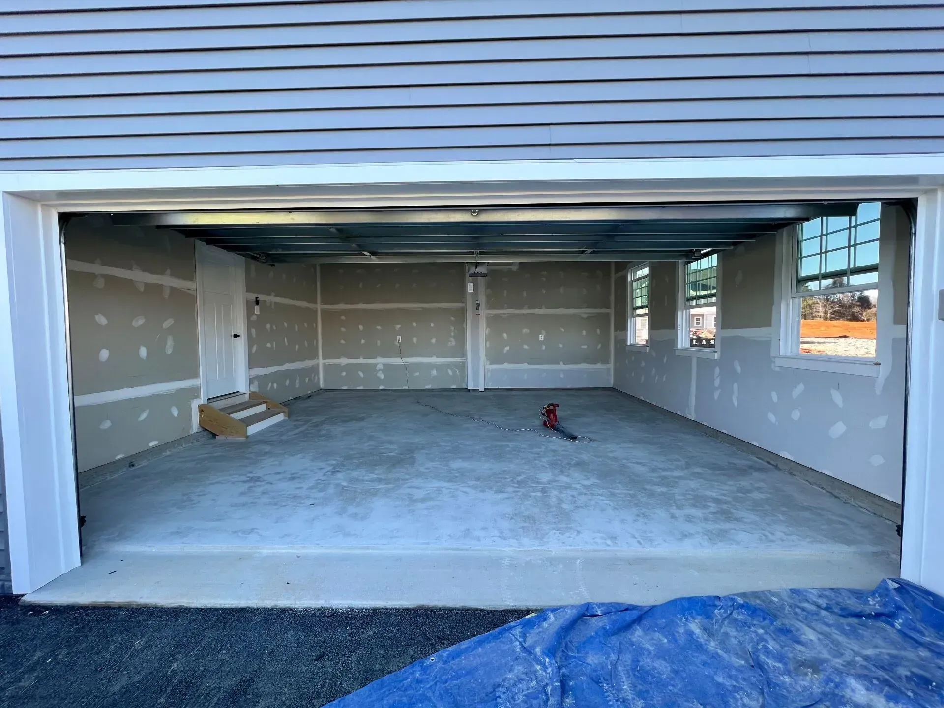 Empty unfinished garage interior with concrete floor, drywall, and open doorway