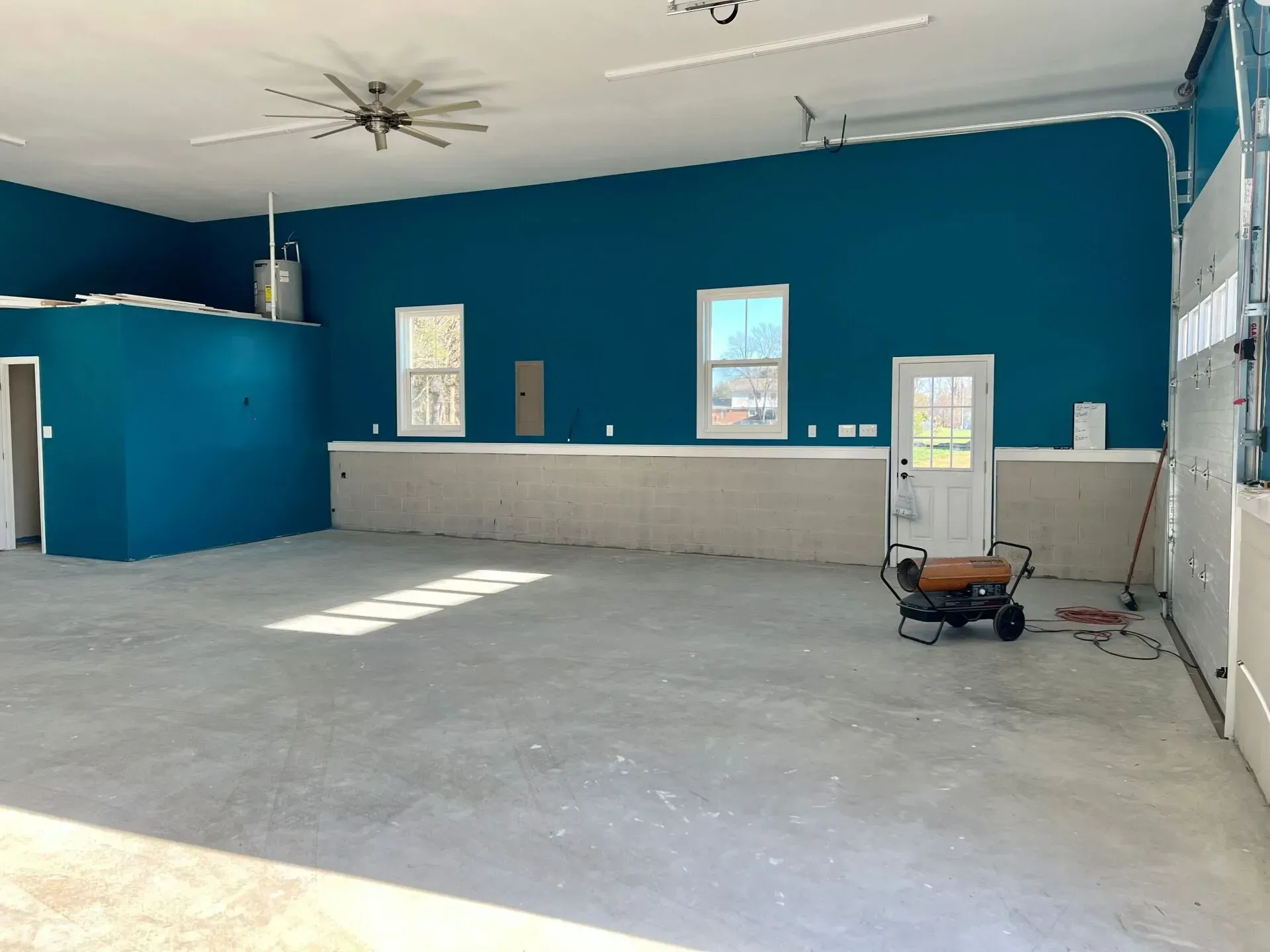 Empty room with blue walls, concrete floor, counter, windows, and a small cart