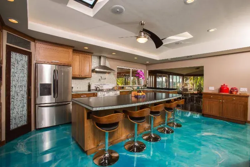 Modern kitchen with turquoise floor, stainless steel appliances, central island, and bar stools