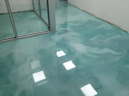 Empty room with glossy turquoise floor and glass sliding door, reflecting ceiling lights.