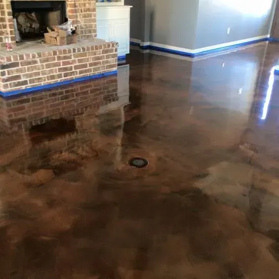 Glossy stained concrete living room floor with blue baseboards and a brick fireplace hearth