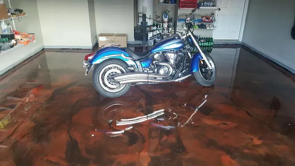 Blue motorcycle parked on a glossy maroon floor in an empty garage.