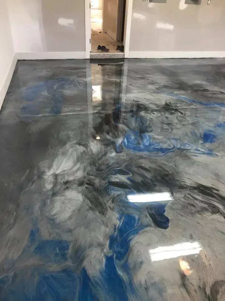 Glossy blue-gray epoxy floor with marbled swirl patterns in an unfinished room