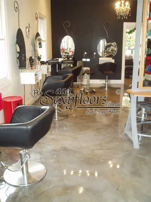 Hair salon interior with black styling chairs, mirrors, and a glossy concrete floor