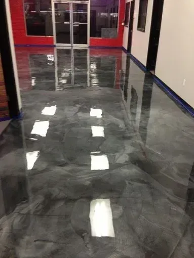 Shiny black epoxy hallway floor with white tile reflections and red doors at the far end