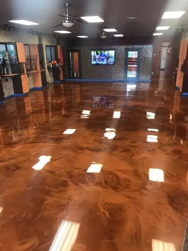 Empty lobby with polished wooden floor, ceiling fans, and a TV on the far wall.