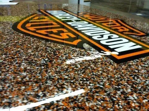 Harley-Davidson logo on a wet, textured floor with orange and black signage.