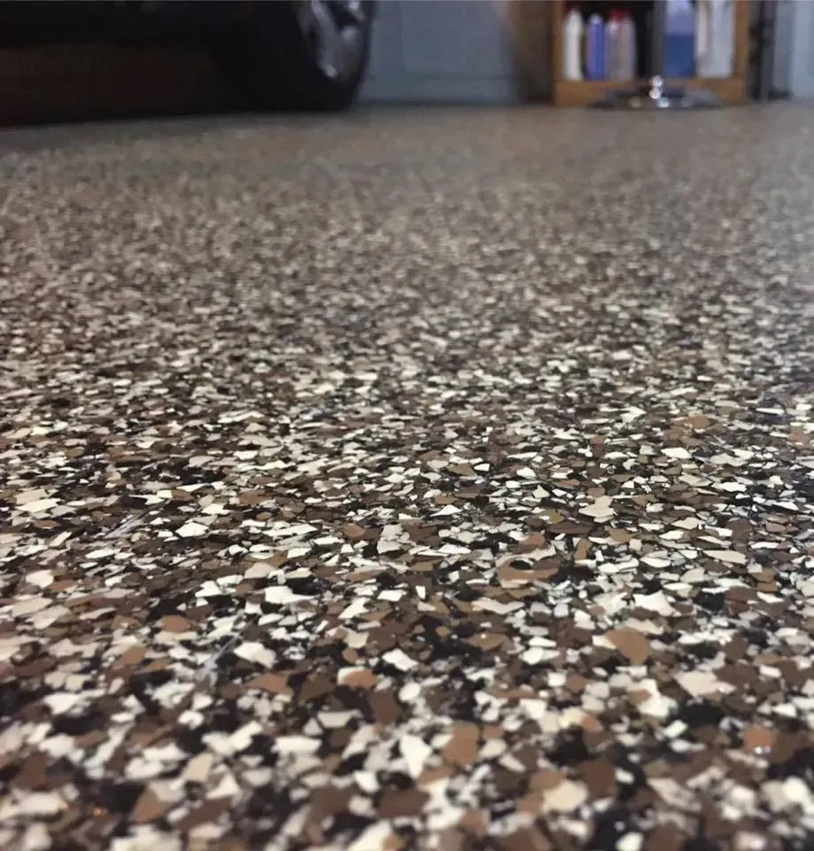Low-angle view of a speckled terrazzo garage floor with a car and shelves blurred in the background