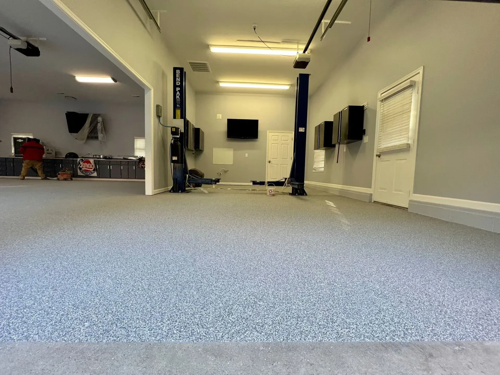 Empty office hallway with blue carpet, white walls, and overhead fluorescent lights