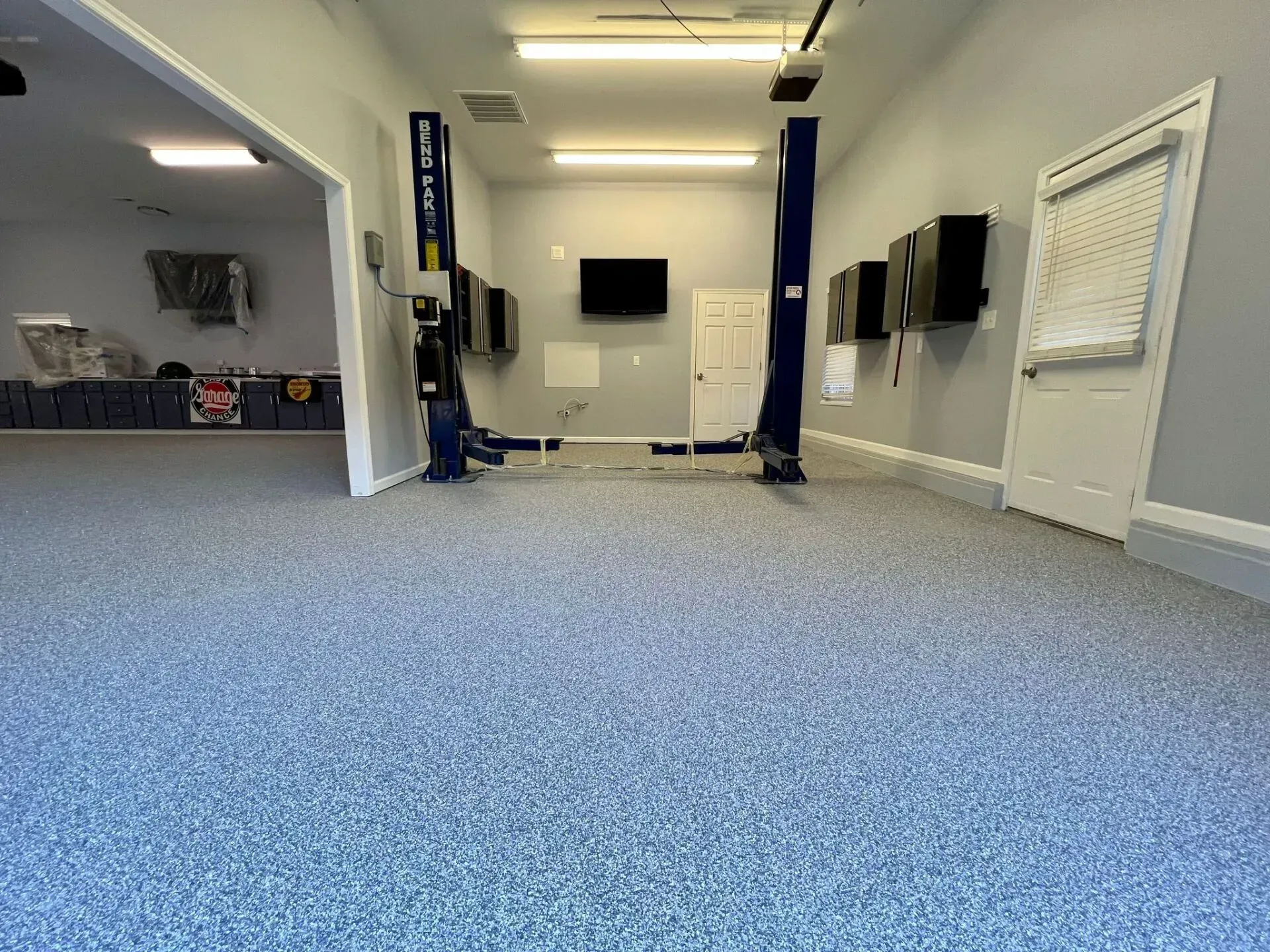 Empty carpeted room with wall-mounted TVs, blue columns, and a small service counter on the left