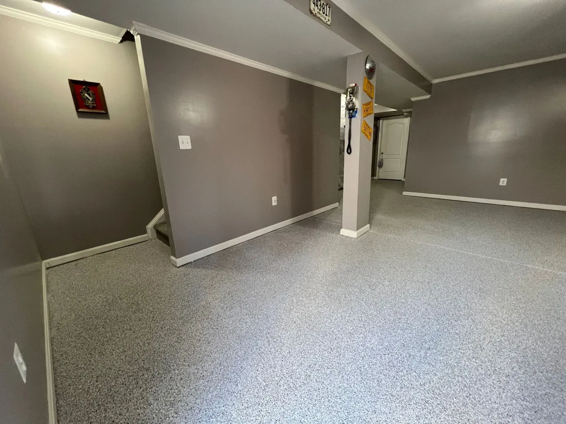 Empty gray room with carpet, support column, and doorway leading to a hallway