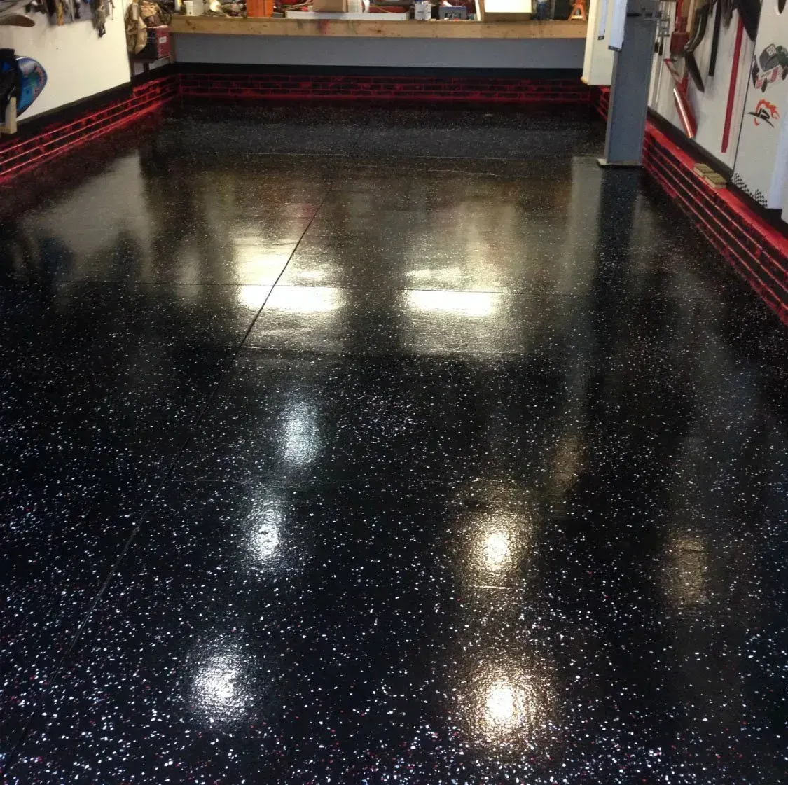 Glossy black-speckled floor in an empty room with shelves and wall decorations along the sides