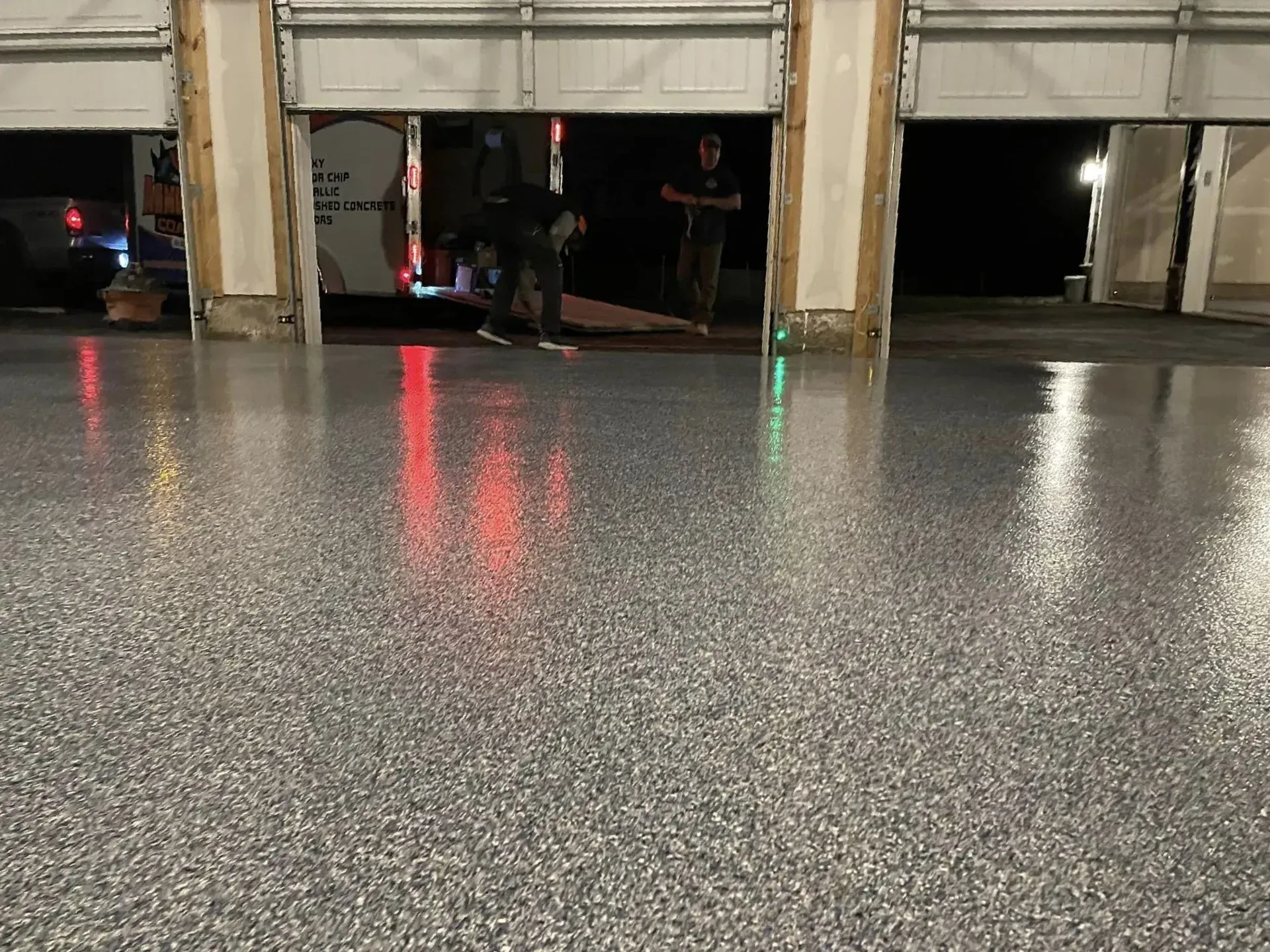 Garage interior with wet reflective floor and a partially open door revealing people inside