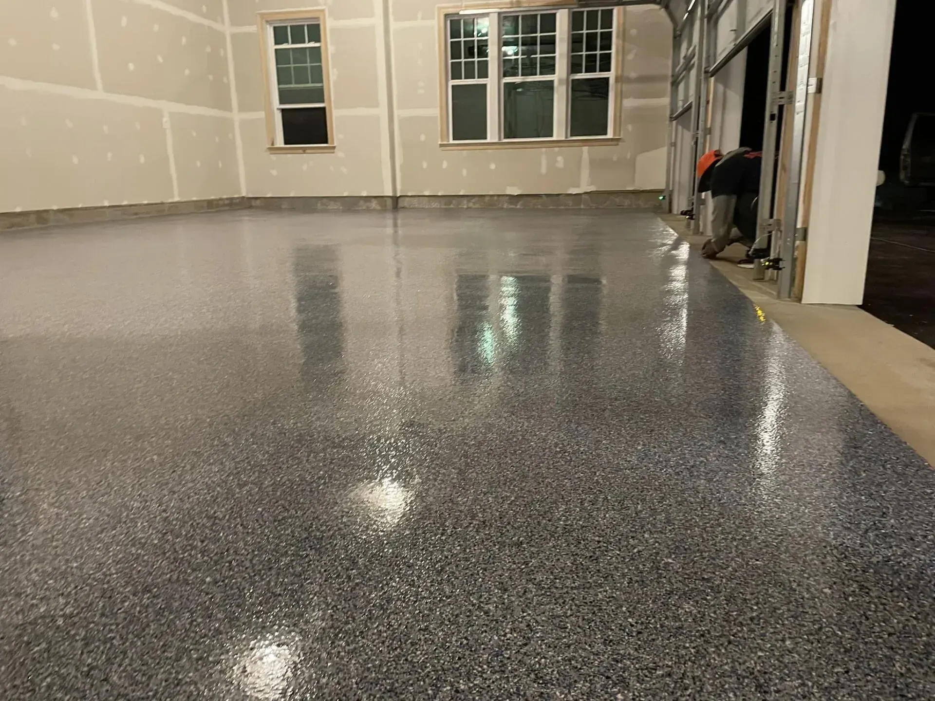 Empty garage with glossy speckled epoxy floor reflecting windows and lights