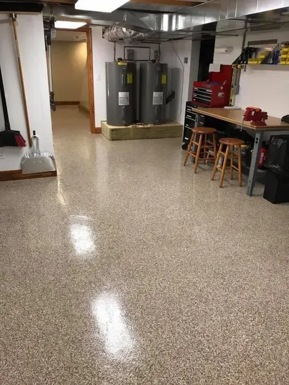 Basement utility room with water heaters, workbench, tools, and polished speckled floor