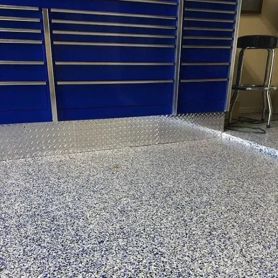 Blue tool drawers and a metal stool in a garage with a speckled epoxy floor.
