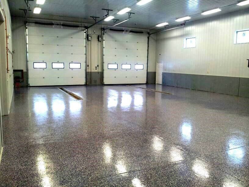 Empty industrial garage with closed white roll-up doors and a polished concrete floor.