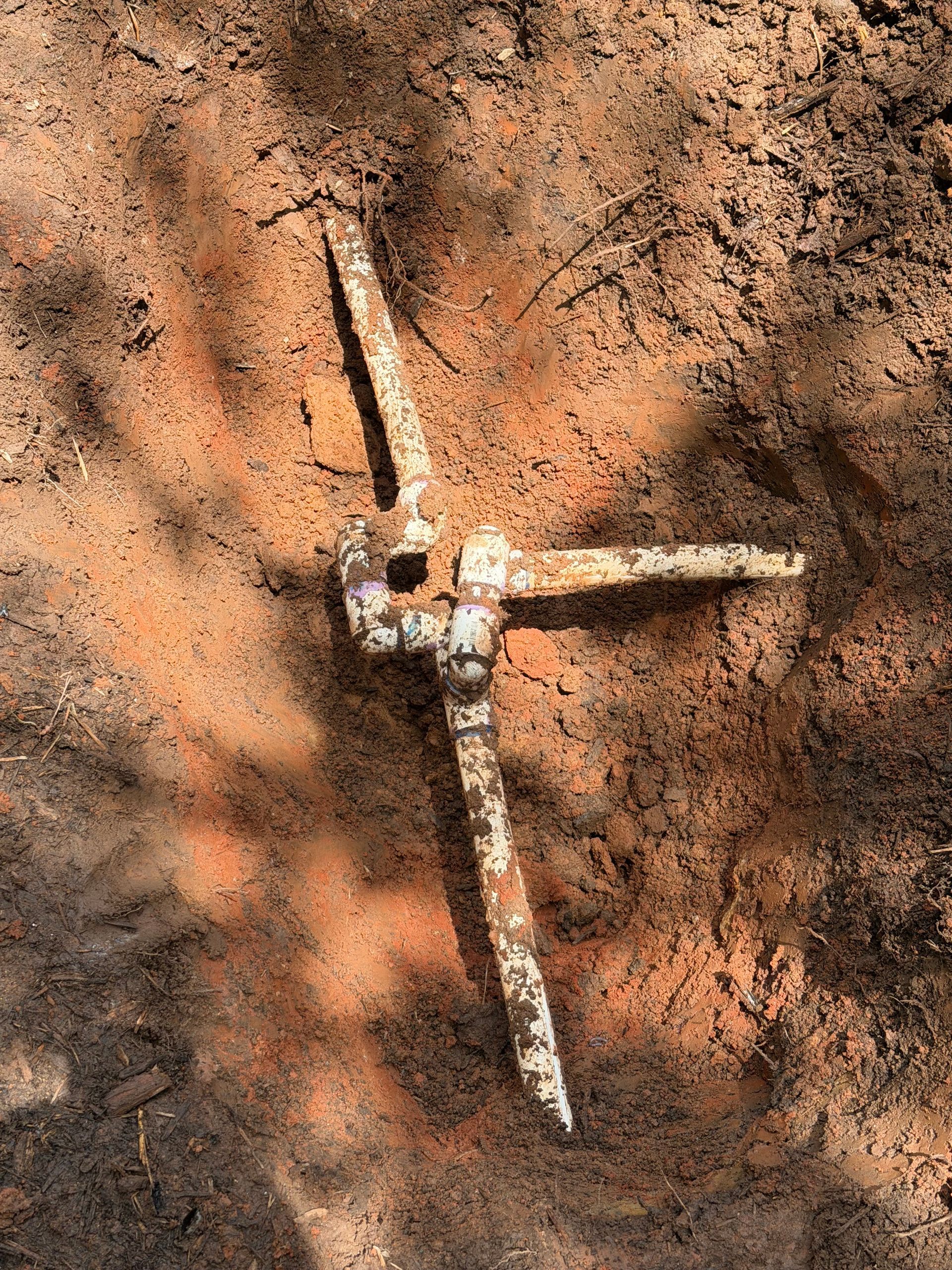 Three weathered white wind turbine blades arranged on dusty brown ground, forming a rough cross shape