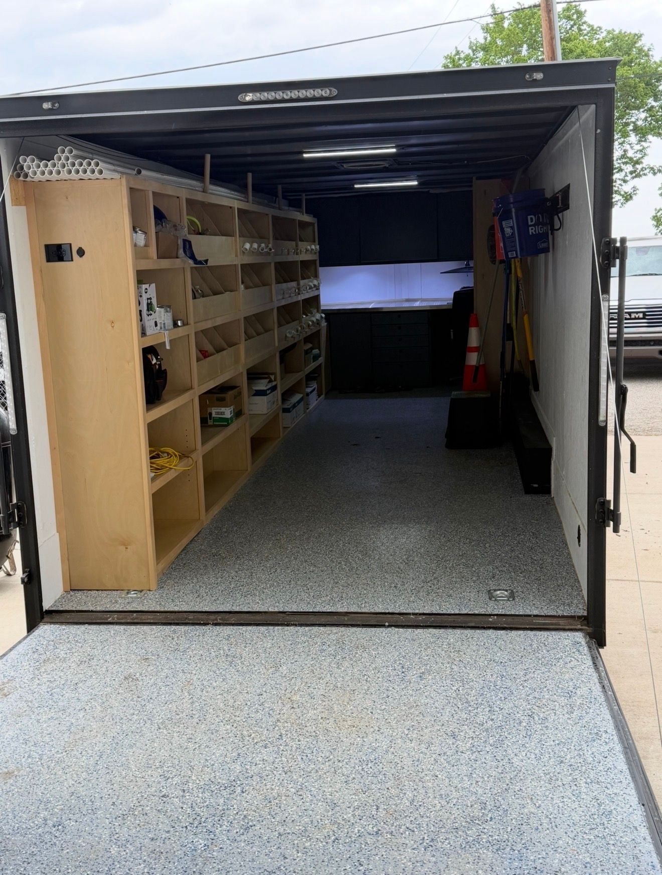 Open shipping container storage with wooden shelves and tools inside, viewed from the open doorway.