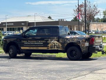 Black pickup truck with gold lettering parked in front of a building on a sunny day