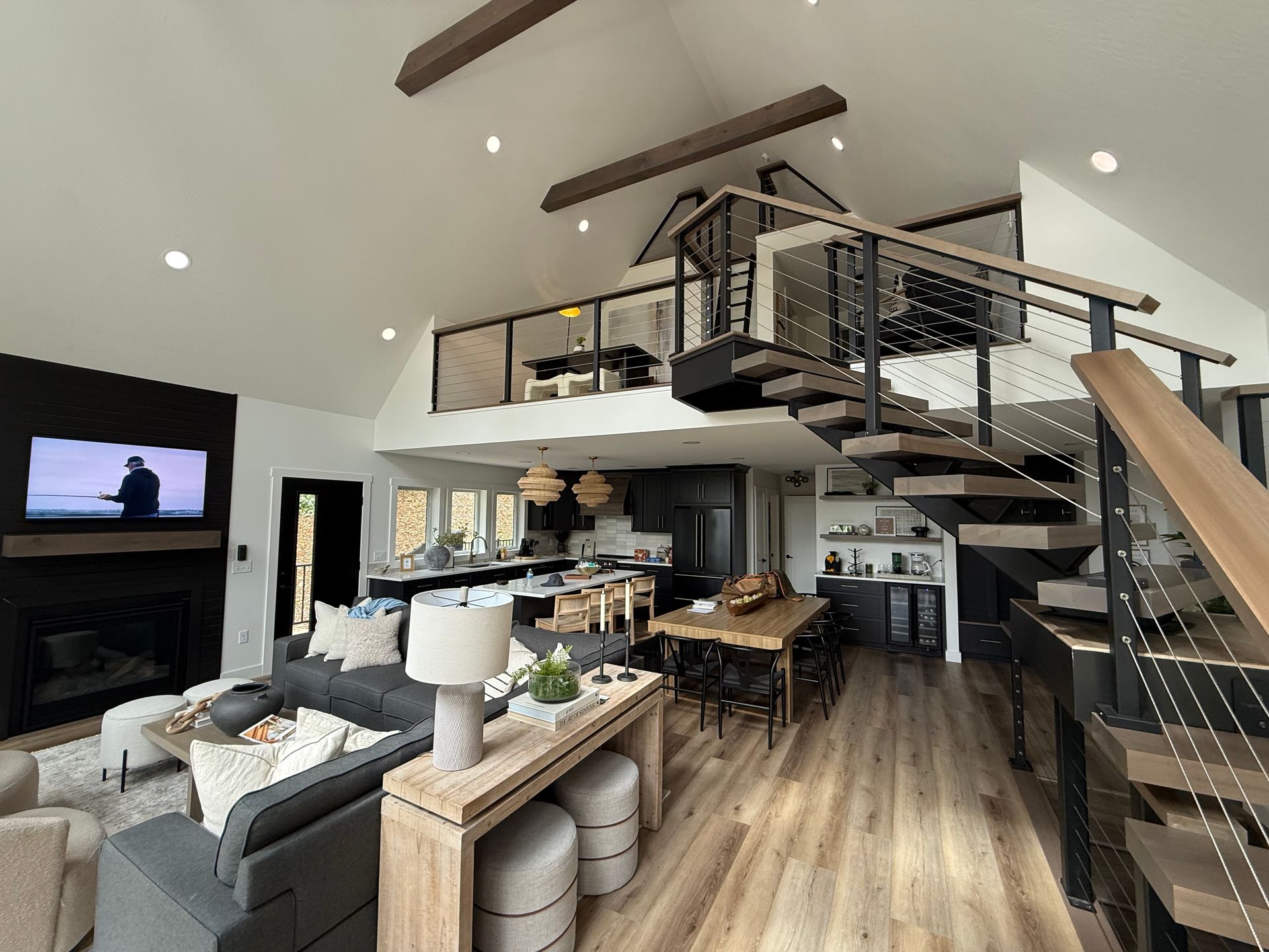Modern open-concept living room with sectional sofa, fireplace, loft, and spiral staircase