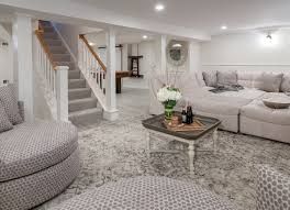 Bright living room with gray sofa, round chair, staircase, and coffee table on a plush rug.