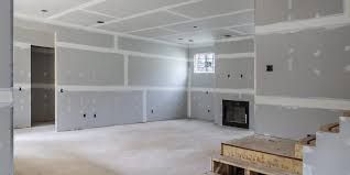 Empty unfinished living room with gray drywall, white floor, and a fireplace under construction