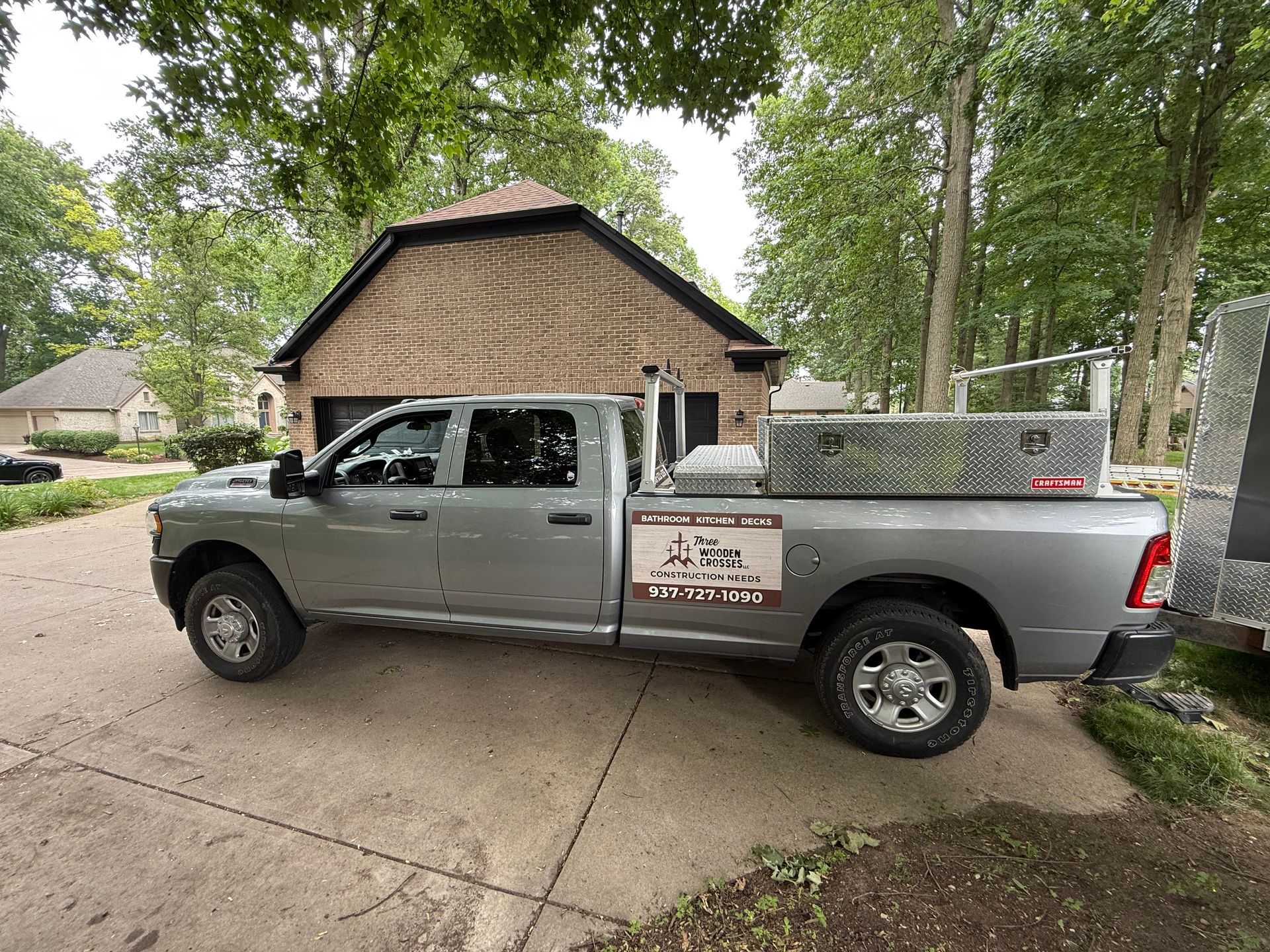 Gray pickup truck parked in a driveway beside a small brick building and trees