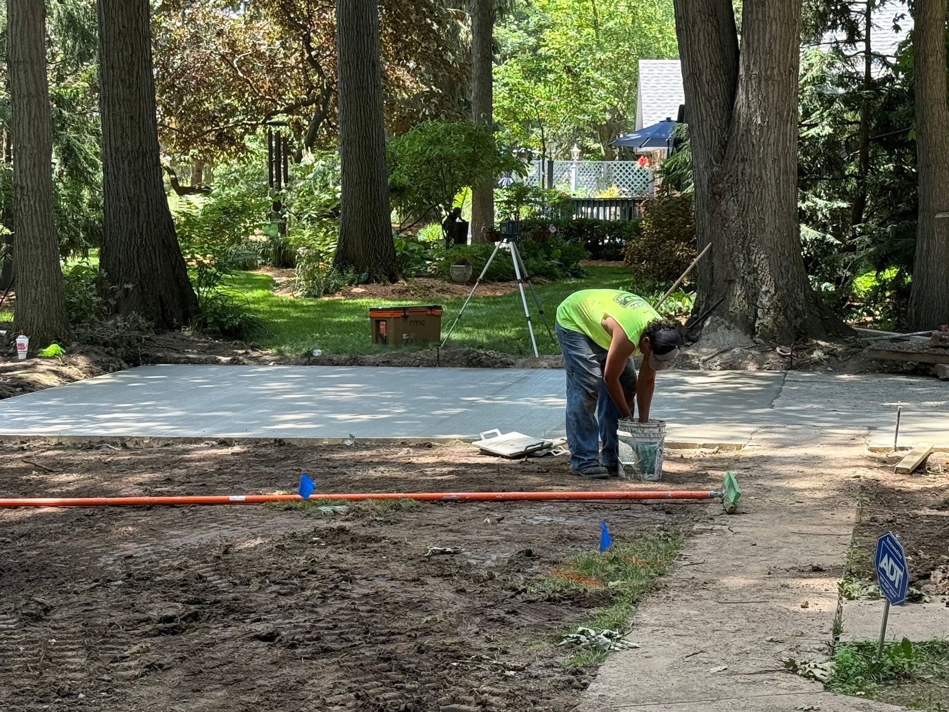 Worker in neon shirt grading a dirt area near a paved path in a wooded park