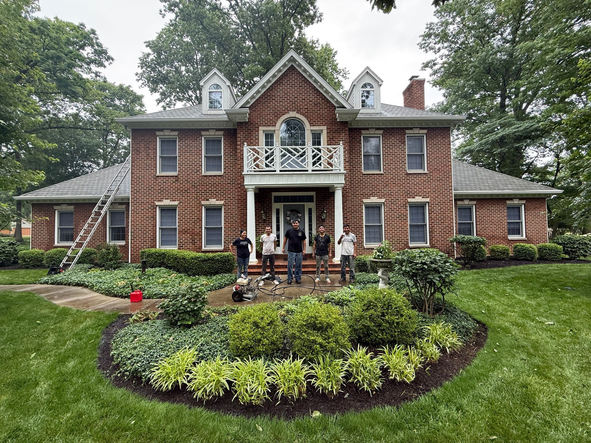 Brick house with white trim and a front porch, framed by a curved flower bed and green lawn