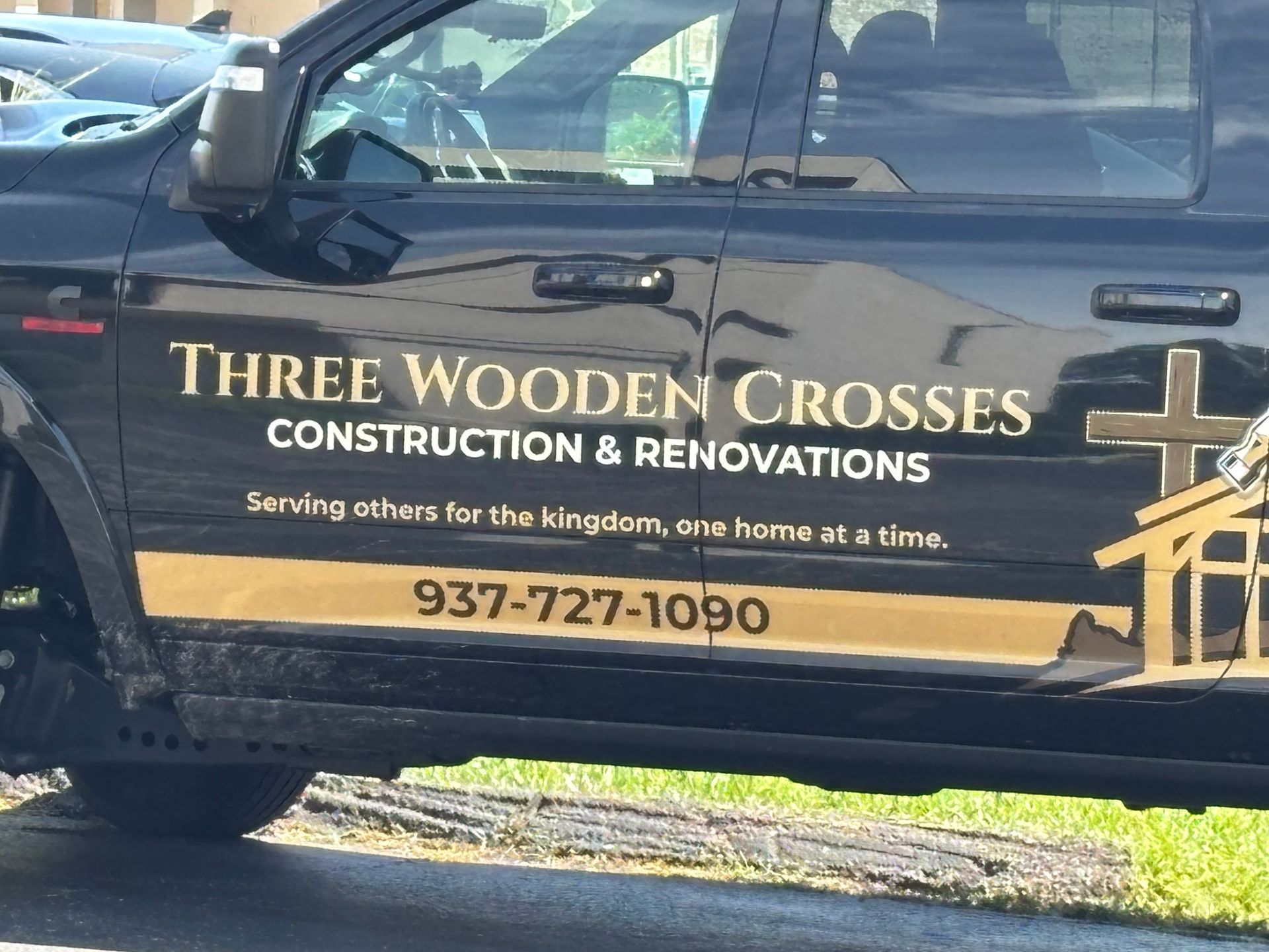 Black truck door with Three Wooden Crosses Construction & Renovations logo and phone number 937-727-1090