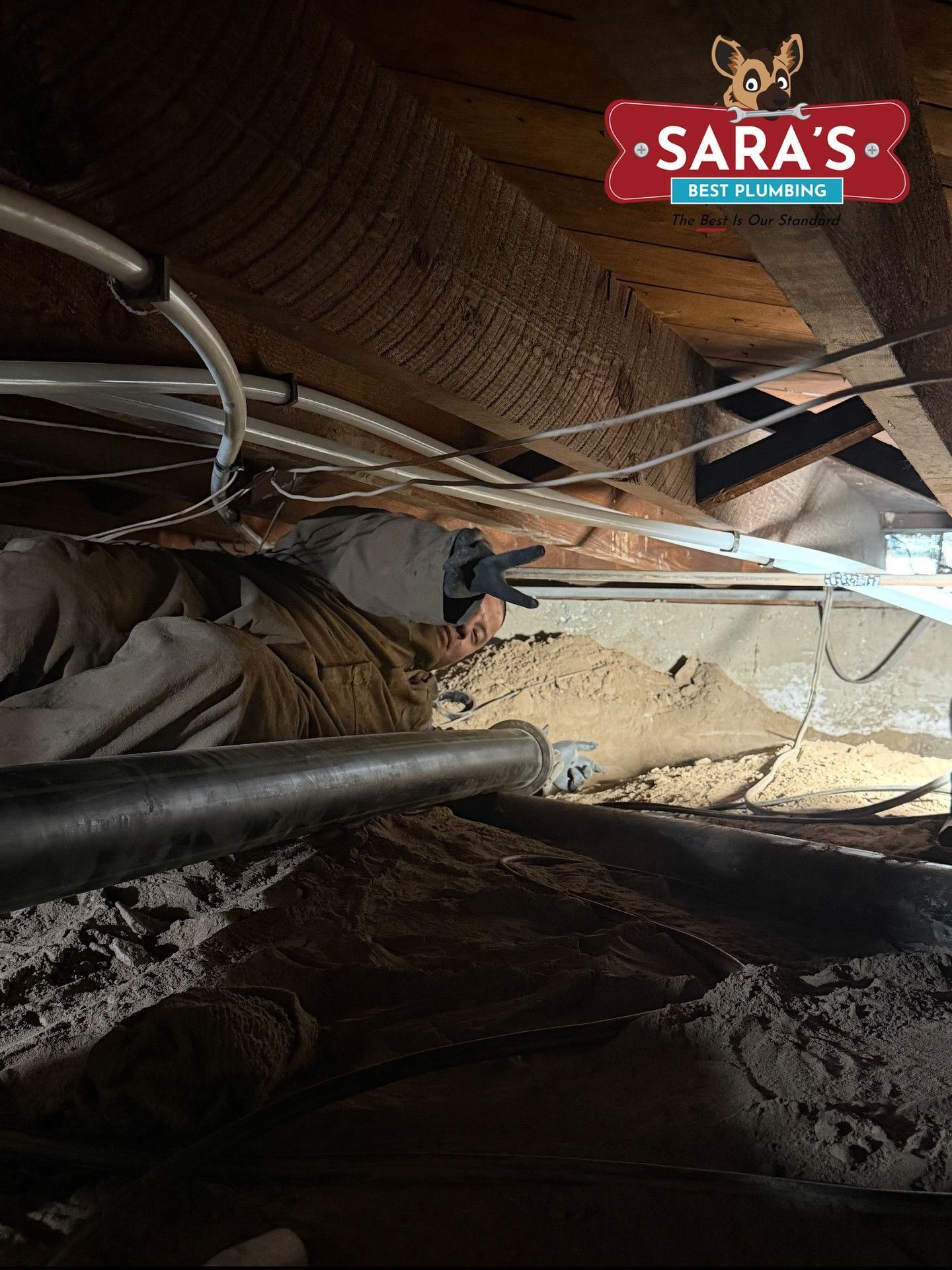 Person in crawl space working; dusty and dark environment.