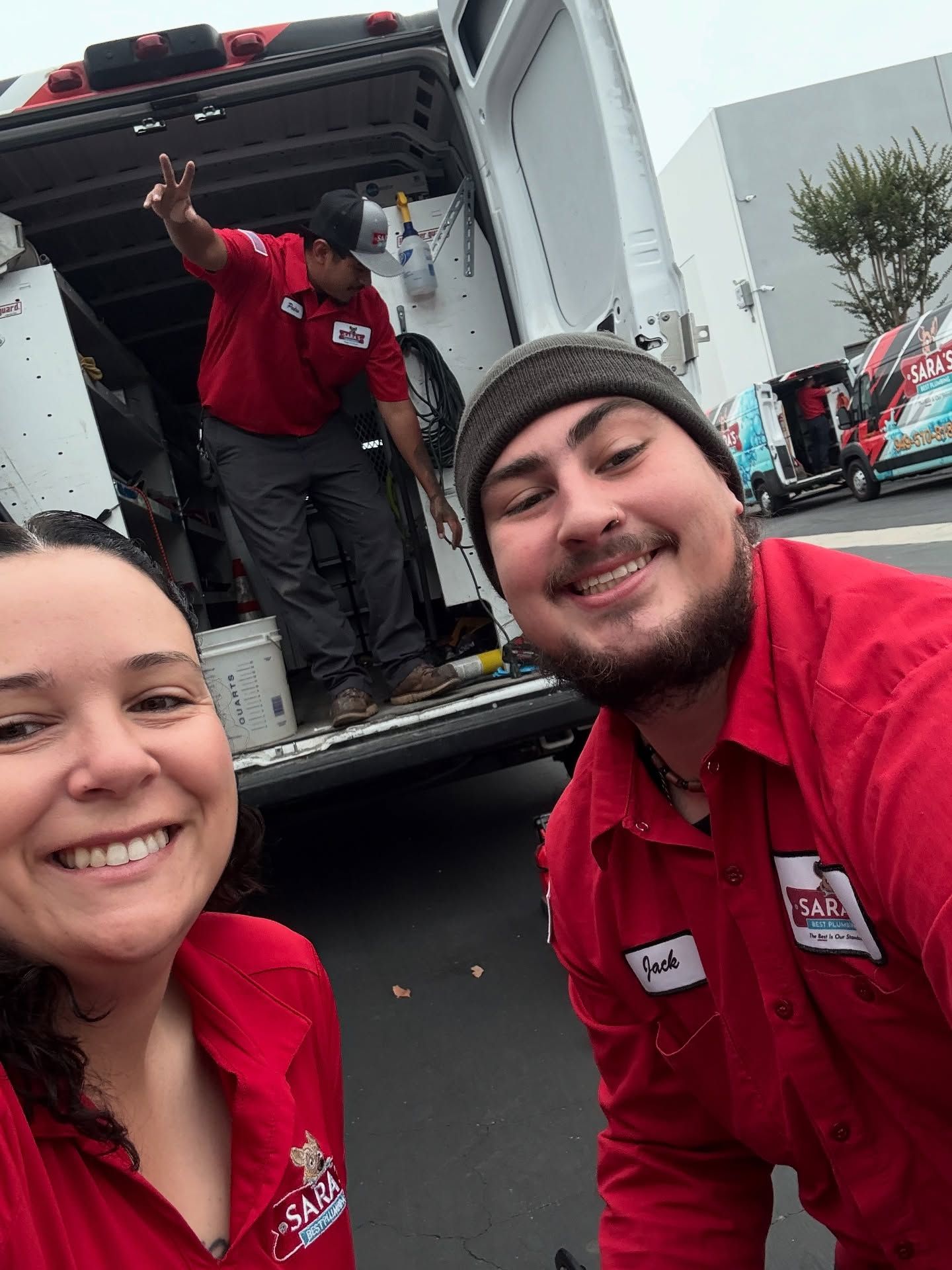 Three technicians in red shirts pose in front of a service van.