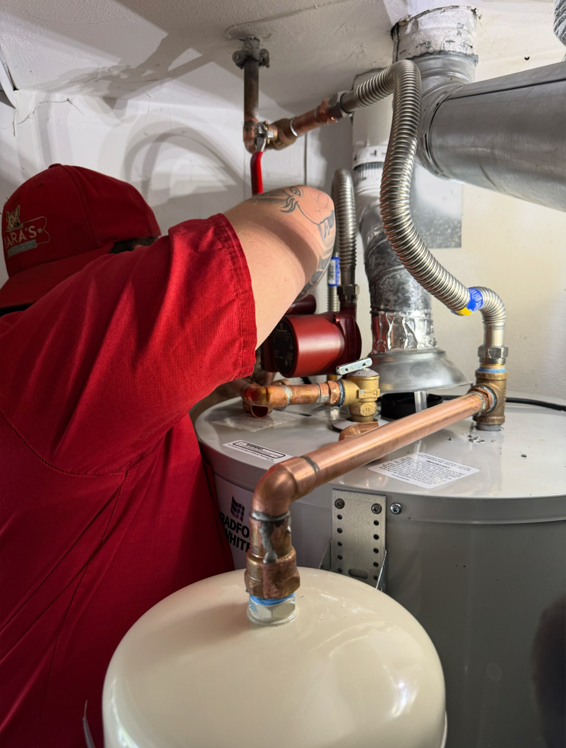 Person in red shirt working on a water heater